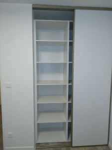 Photo de galerie - Pose d'un aménagement de placard avec rayonnages et penderie, intégré derrière des portes coulissantes existantes pour optimiser l'espace