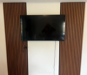 Photo de galerie - Installation d’un mur décoratif en tasseaux de bois derrière la TV