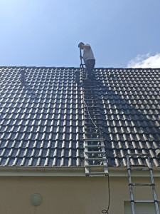 Photo de galerie - Notre technicien en action, éliminant mousse et lichens de votre toiture avec un équipement haute pression. Un entretien essentiel pour préserver vos tuiles et l'esthétique de votre maison.