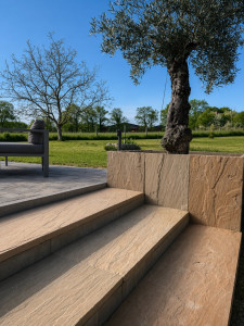 Photo de galerie - Mélange harmonieux de pierre effet naturel, de finitions contemporaines et de végétation pour créer une terrasse élégante, chaleureuse et parfaitement intégrée à son environnement.