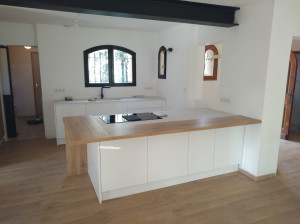 Photo de galerie - Cuisine moderne blanche avec grand îlot central, plan de travail effet bois et finitions soignées.