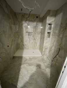 Photo de galerie - énovation complète d'une salle de bain moderne avec douche à l'italienne, carrelage grand format et meuble vasque suspendu.