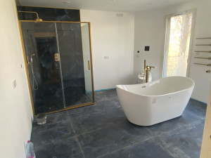 Photo de galerie - Ici, toutes les conduites d'eau ont été remplacées, après quoi une nouvelle douche avec un robinet mural intégré a été installée, puis une baignoire a été installée au centre de la pièce avec un robinet au sol et des toilettes électriques.