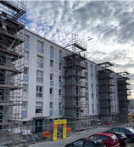 Photo de galerie - Création de plusieurs gaines d’ascenseur en béton armé sur bâtiment existant. Structures porteuses lourdes avec reprises de charges importantes. Échafaudages en place sur toute la hauteur de façade.
