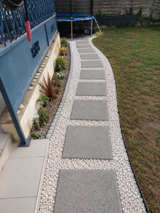 Photo de galerie - Création et aménagement d’une allée extérieure avec pose de dalles, mise en place de graviers décoratifs et finition soignée des bordures. Un résultat propre, esthétique et durable