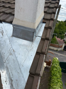 Photo de galerie - Travaux de zinguerie : réalisation d’un abergement de cheminée en zinc avec raccordement à la couverture en tuiles pour assurer l’étanchéité de la toiture.