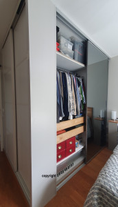 Photo de galerie - Double dressing angulaire autour d'un meuble Ikéa Pax, 2 grandes portes coulissantes miroir et 2portes coulissantes blanches dans l'entrée. Aménagement sur mesure avec cloison de 40cm.