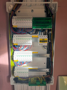 Photo de galerie - Tableau électrique mural moderne installé chez un client, équipé de disjoncteurs et de barrettes de terre, répondant aux normes locales de sécurité.