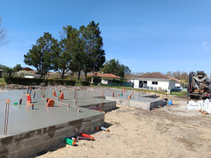 Photo de galerie - Réalisation de 4 maisons individuelles en cours : fondations et dalles béton. Chantier de gros œuvre avec réseaux déjà en place. Travail soigné et structuré.