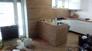 Photo de galerie - Rénovation complète d’une cuisine – conception, aménagement, pose et finitions. Réalisation sur mesure avec habillage mural et création d’un espace bar.
