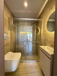 Photo de galerie - Rénovation de salle de bain avec pose de carrelage grand format effet marbre blanc, revêtement mural et sol, réalisation de finitions soignées pour un rendu moderne, élégant et haut de gamme.