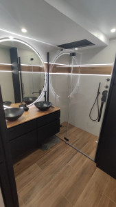 Photo de galerie - Réalisation complète d’une salle de bain du sol au plafond : chape, doublages et préparation des supports.  Pose de carrelage grand format 150 x 75 cm en carreaux de grande qualité, avec frise bois et intégration d’un bandeau LED spécial salle de bain.