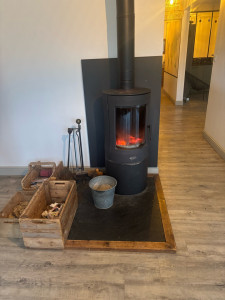 Photo de galerie - Installation d’un poêle sur une plaque d’ardoise avec cadre en bois.