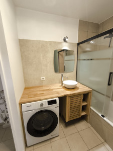 Photo de galerie - Habillage d'un mur en travertin, création d'un meuble sur mesure, pose d'une vasque, d'un miroir et d'une paroie de douche. 