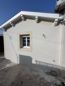 Photo de galerie - Enduit couleur gratter fin neige avec bandeaux en fausse pierre de plaquage autour des ouverture dans les angles et sous débord de toit de couleur guerande 