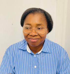 Photo de galerie - C'est un portrait en gros plan d'une femme portant une chemise rayée bleue et blanche et des lunettes à monture métallique dorée.