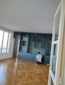 Photo de galerie - Montage et agencement d'un meuble bibliothèque sur mesure dans un salon.