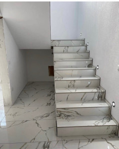Photo de galerie - Pose de carrelage grand format effet marbre sur sol et escalier. Habillage complet des marches avec découpes précises, alignement des veines pour un rendu esthétique et haut de gamme. Finitions soignées avec joints réguliers.