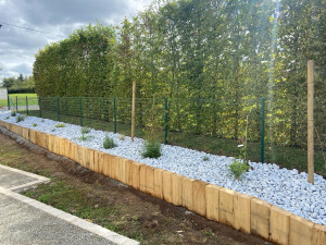 Photo de galerie - Création d’un massif avec des poutres en chêne pose de galets blanc et plantation de plantes