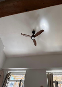 Photo de galerie - Installation d’un ventilateur au plafond dans une pièce, avec fixation sécurisée et branchement électrique propre