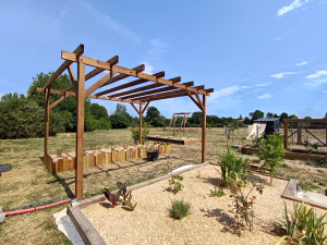 Photo de galerie - Création pergola décorative avec parterre paysagé d'un côté et jardinière autoportée de l'autre .