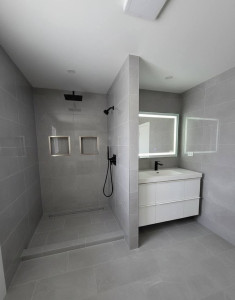 Photo de galerie - énovation complète d'une salle de bain moderne avec douche à l'italienne, carrelage grand format et meuble vasque suspendu.