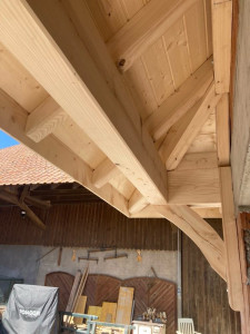 Photo de galerie - Auvent au dessus d’un garage en bois raboté avec lambris sur chevrons avec couverture