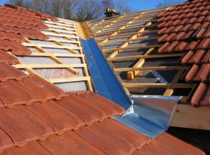 Photo de galerie - Toiture en rénovation présentant des tuiles neuves et une noue en zinc parfaitement réalisée. 