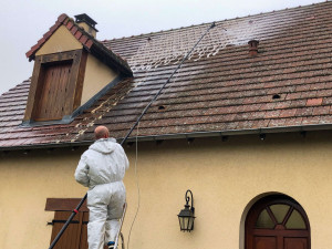 Photo de galerie - Nettoyage complet d’une toiture en tuiles avec traitement démoussant. Intervention en hauteur avec perche télescopique pour éliminer mousses et dépôts avant l’application d’un traitement de protection. 