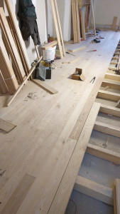 Photo de galerie - Installation complète d’un parquet stratifié avec découpes précises et finitions soignées. Alignement parfait des lames pour un rendu moderne et chaleureux.