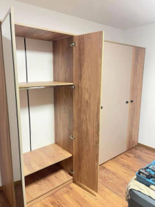 Photo de galerie - Montage et installation d’un dressing sur mesure avec étagères de rangement, portes battantes et réglage des charnières. Travail soigné et finitions propres.