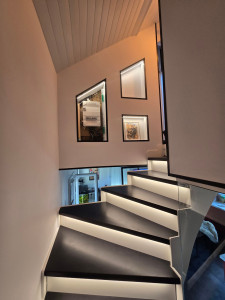 Photo de galerie - Escalier metal avec marches en hêtre teintées éclairées. 