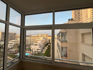 Photo de galerie - Loggia fermée par une menuiserie aluminium coulissante deux vantaux, comprenant une imposte fixe en partie haute. L’ensemble est complété sur le côté gauche par un châssis fixe avec traverse intermédiaire horizontale en partie haute, assurant rigidité