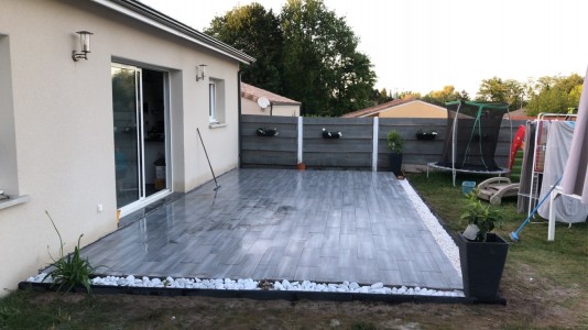 Photo de galerie - Terrasse béton avec pose carrelage + cailloux et bordure aménagement paysager. 