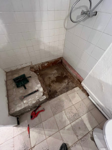 Photo de galerie - Le bac à douche a été retiré, laissant apparaître le sol brut et l’évacuation d’eau. L’ensemble est prêt pour une remise en état avec une nouvelle installation L’espace est dégagé, offrant une base propre pour un travail soigné et durable.