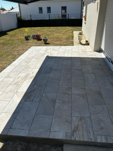 Photo de galerie - Réalisation d’une terrasse extérieure avec pose de carrelage effet pierre naturelle ! Un travail soigné et des finitions précises pour créer un espace moderne, élégant et convivial. Un beau résultat qui valorise l’extérieur de la maison !