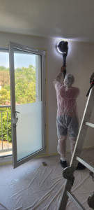 Photo de galerie - Préparation minutieuse des murs : ponçage intégral à la ponceuse girafe avec aspiration et protection complète du chantier avant mise en peinture.