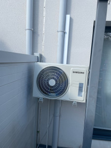 Photo de galerie - Installation d’une unité extérieure Samsung avec fixation sécurisée, raccordements frigorifiques et électriques, essais de fonctionnement validés.
