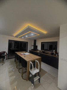 Photo de galerie - Plafond moderne réalisé en coffrage avec LED intégrées, créant une lumière d’ambiance élégante au-dessus de l’îlot central.
Un rendu propre, contemporain et parfaitement intégré à la cuisine.