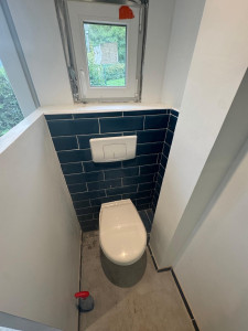 Photo de galerie - Installation d’un WC suspendu avec habillage du bâti-support et pose de carrelage mural. Finitions propres et alignements soignés pour un rendu moderne et durable.