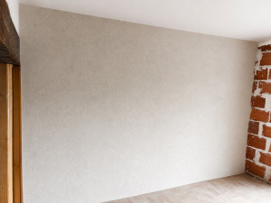 Photo de galerie - Application d'un enduit décoratif au plâtre gratté, teinte Sable de Loire, sur support en parpaings. Finition soignée pour un rendu esthétique et durable.