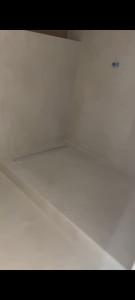 Photo de galerie - Pose de carrelage dans une salle de bain, avec réalisation du sol et des finitions autour de la douche. Travail soigné et finitions propres.