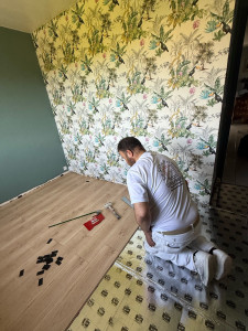Photo de galerie - Pose d'un revêtement de sol en parquet stratifié avec installation de la sous-couche isolante. Travail précis pour un sol parfaitement aligné et durable.