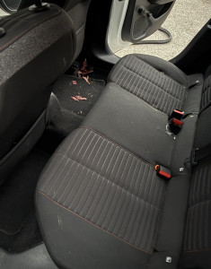 Photo de galerie - Photo avant nettoyage : sièges arrière avec poussière, miettes et résidus visibles. Cet état initial montre le travail à réaliser avant le passage de l’aspirateur et de la shampooineuse pour un résultat impeccable.