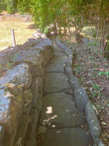 Photo de galerie - Cette épaisse muraille côtoient pudiquement le massif grâce à un drain en lauze, charmant et simple d'entretien.
