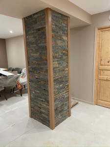 Photo de galerie - Un simple poteau porteur transformé en véritable atout déco !  Parement en pierre naturelle et finitions en chêne massif pour un rendu élégant et chaleureux.