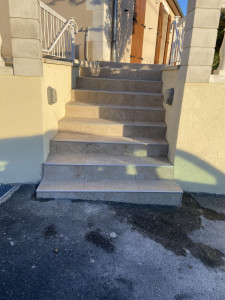Photo de galerie - Réalisation complète d’un escalier extérieur carrelé, avec pose précise des marches et contremarches, nez de marche, alignement soigné et finitions propres et durables.