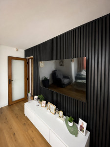 Photo de galerie - Réalisation d’un mur décoratif avec pose de panneaux acoustiques à tasseaux de bois, installation électrique, création des alimentations et pose murale de la télévision avec câblage dissimulé.