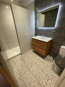 Photo de galerie - Murs habillés de faïence 3D – reliefs subtils & modernité  Sol en terrazzo, graphique et intemporel  Plomberie Grohe pour un confort durable  WC d’origine conservé selon le choix du client Un espace rénové avec soin, entre caractère et fonctionnalité 