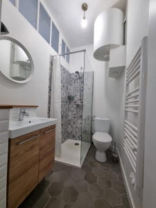 Photo de galerie - énovation d'une salle d'eau à Bayonne avec un budget maîtrisé. Pose de faïence murale à motifs et sol en carreaux hexagonaux. Installation d'un meuble vasque aspect bois et d'une paroi vitrée. Une solution économique et esthétique pour optimiser l'espace 